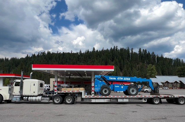 Truck transporting construction equipment at gas station