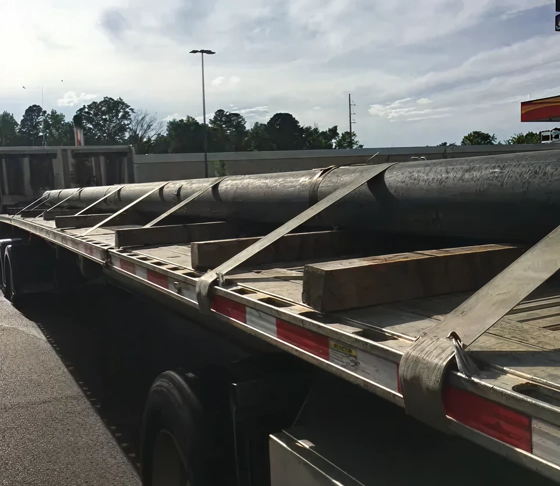 Flatbed truck with large metal pipes