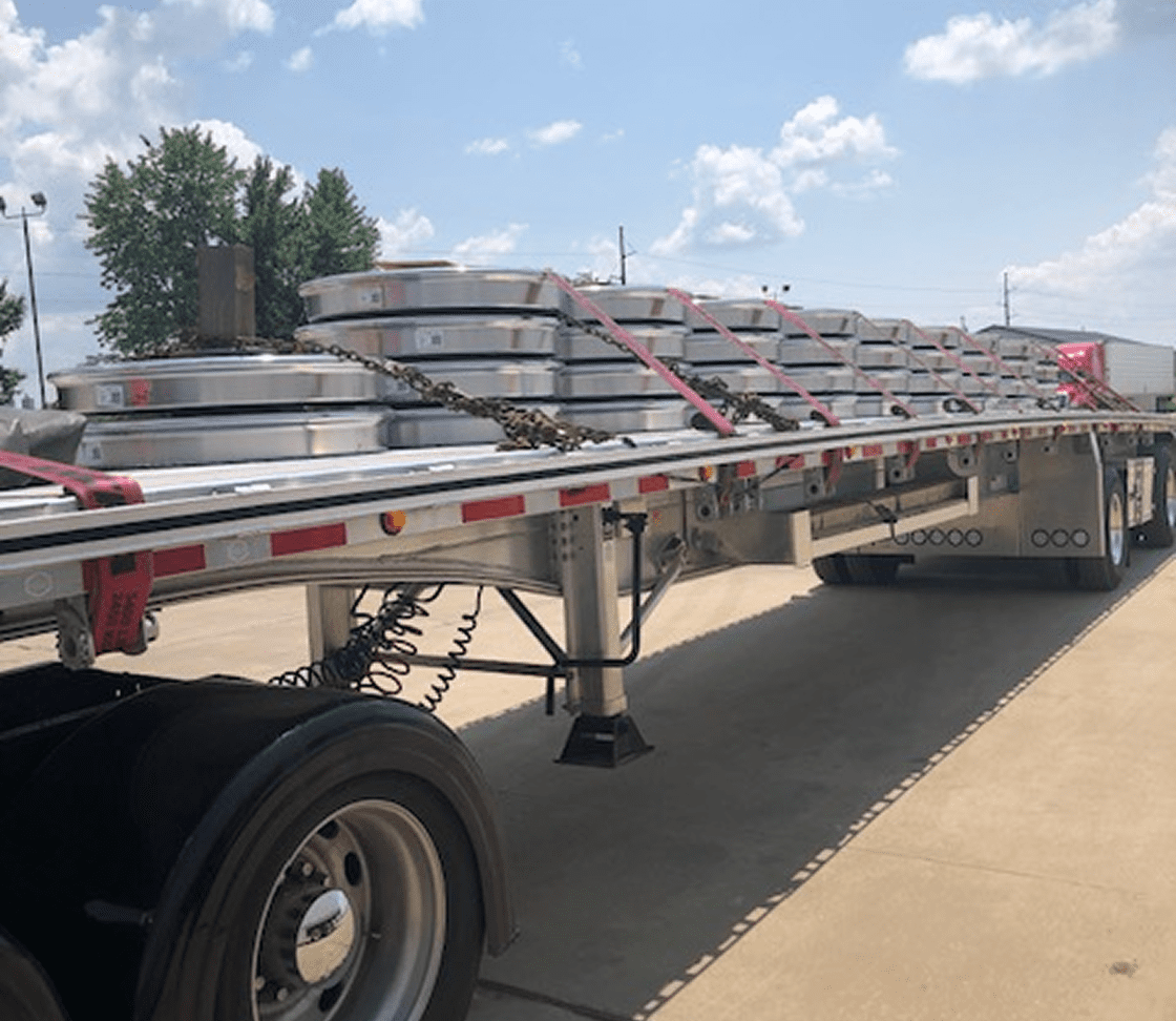 Securing a full truckload of heavy machinery for transport.